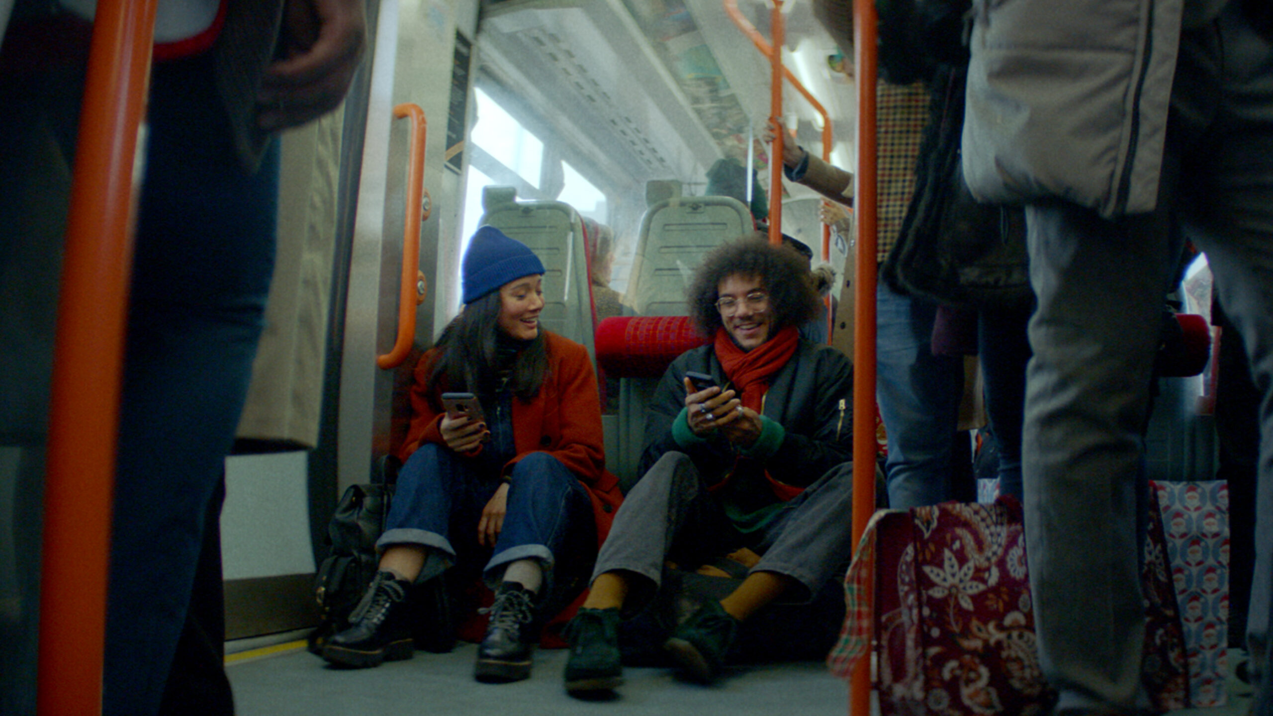 Man and woman holding mobile phones on a bus